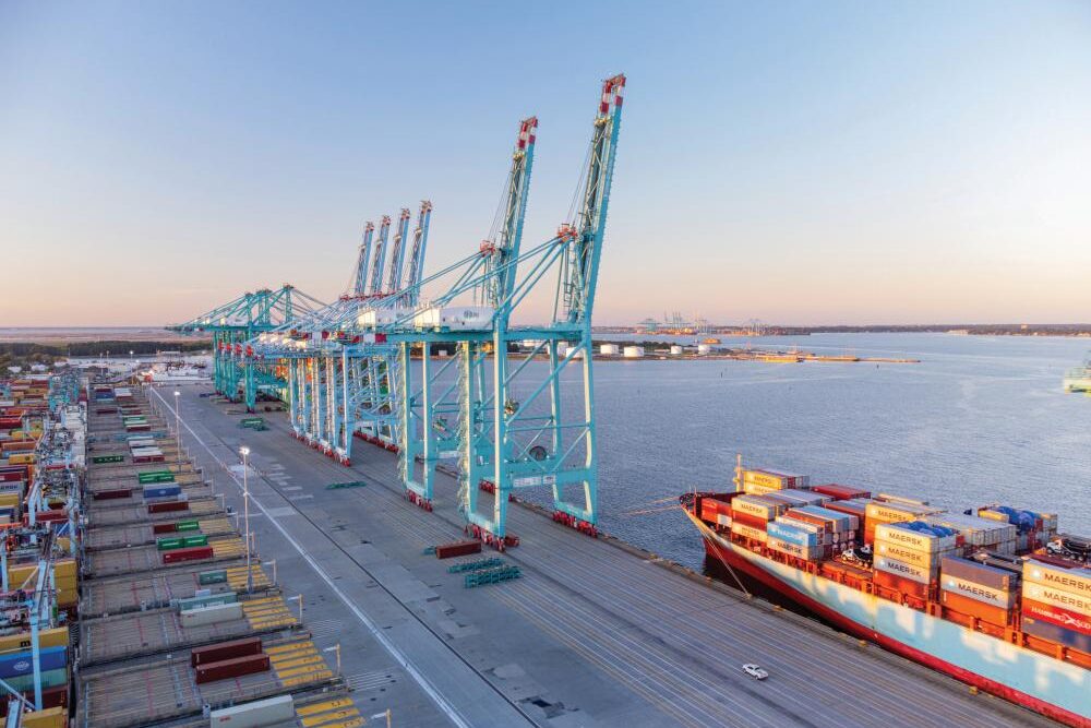 assive cranes unload Maersk cargo containers at the Port of Virginia during golden hour, capturing the scale of maritime trade and logistics.