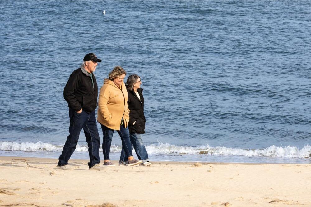 People walk along the beach near Fort Monroe.