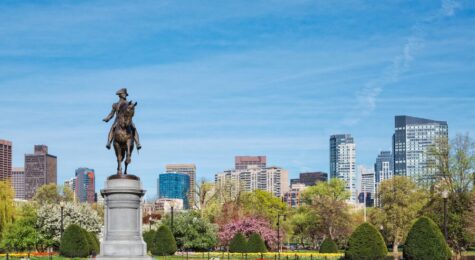 Equestrian bronze statue of General George Washington in the Boston Public Garden surrounded by green trees.