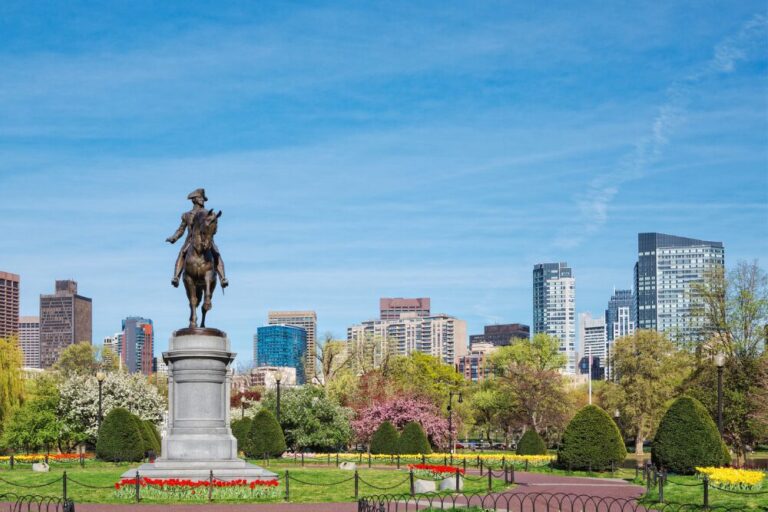 Equestrian bronze statue of General George Washington in the Boston Public Garden surrounded by green trees.