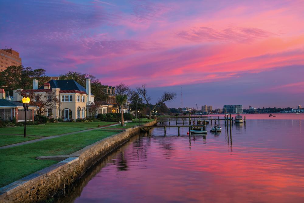 Houses and Riverfront of the Elizabeth River in Portsmouth, Virginia during dawn with magenta, purple, and pink clouds. Portsmouth, VA is part of the Virginia Beach / Hampton Roads metropolitan area.