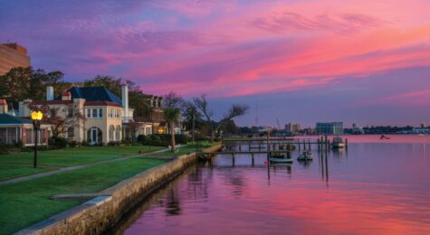 Houses and Riverfront of the Elizabeth River in Portsmouth, Virginia during dawn with magenta, purple, and pink clouds. Portsmouth, VA is part of the Virginia Beach / Hampton Roads metropolitan area.