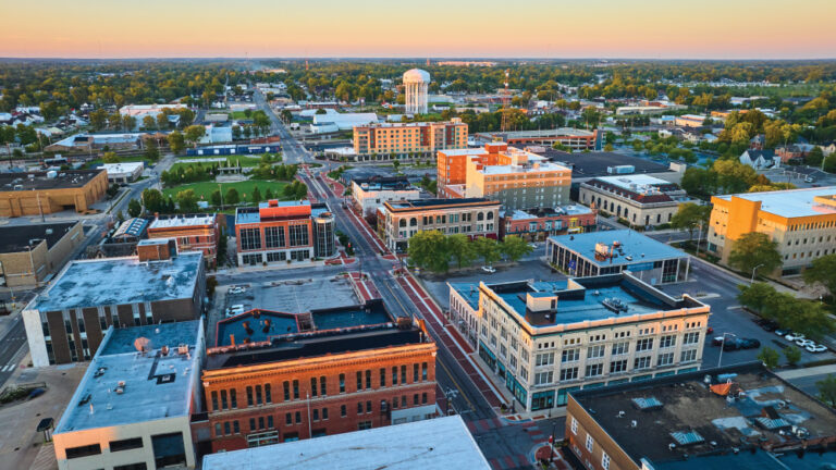 Image of Downtown Muncie Indiana aerial at dawn with yellow sunrise lighting on buildings and water tower