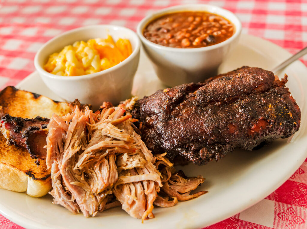 A combination plate of smoked ribs, pulled pork and brisket is served with macaroni and cheese and baked beans.