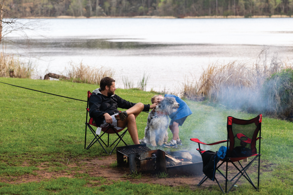 Families enjoy a camp fire next to the lake while camping at Big Pine Campgrounds at Tyler State Park in Tyler, Texas.