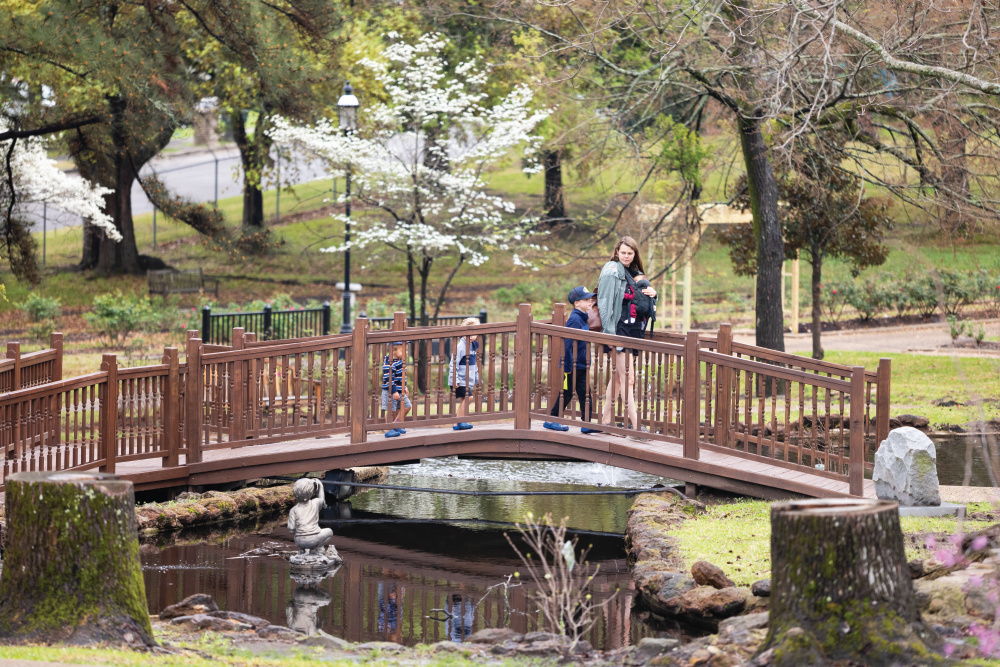 Visitors view the koi pond from a bridge at Tyler Rose Garden in Tyler, Texas.