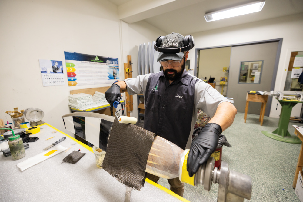 Joey Rivera glues strips of fiberglass to a wooden aircraft propeller at M T Propeller USA