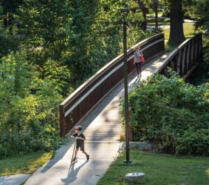 Visitors cross a bridge across Ioway Creek at Brookside Park in Ames, Iowa.
