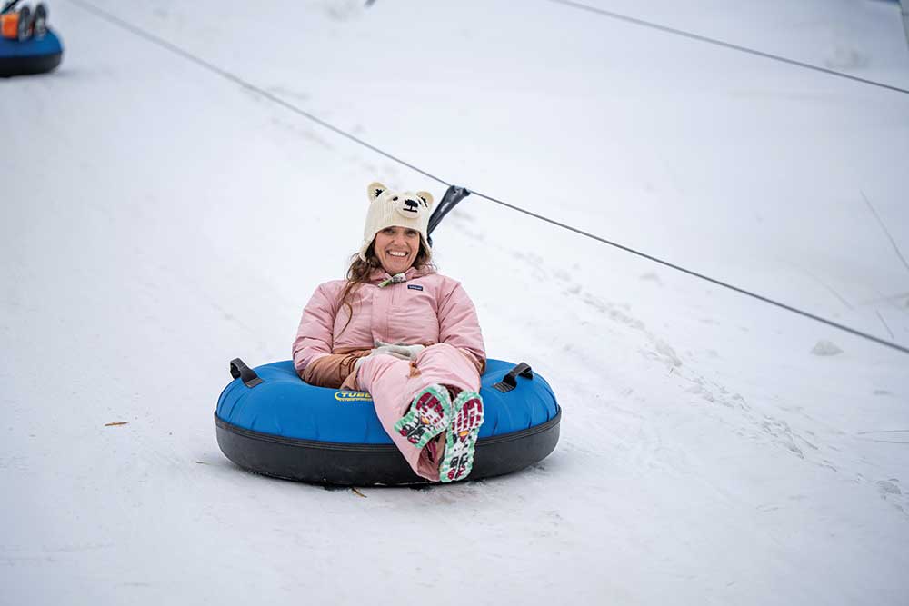 Child racing down the snow tubing lanes at Seven Oaks Recreation during a classic central Iowa winter.