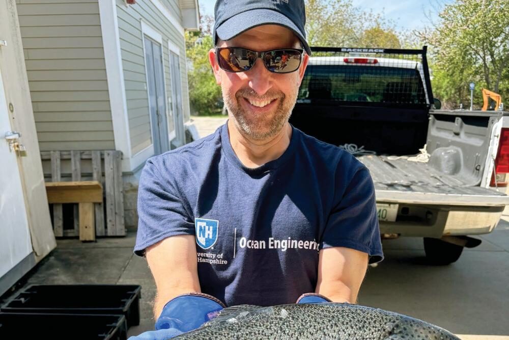 UNH team member with a fish cultivated in the Aqua Fort