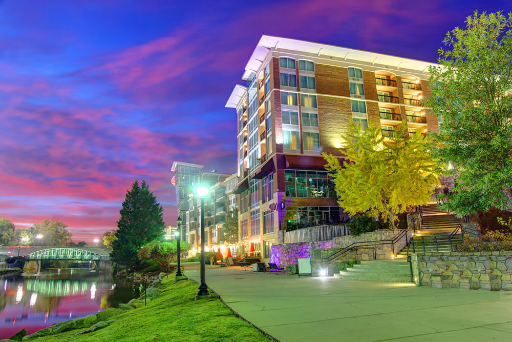 The Greenville, South Carolina, waterfront along the Reedy River is lit up at dusk.