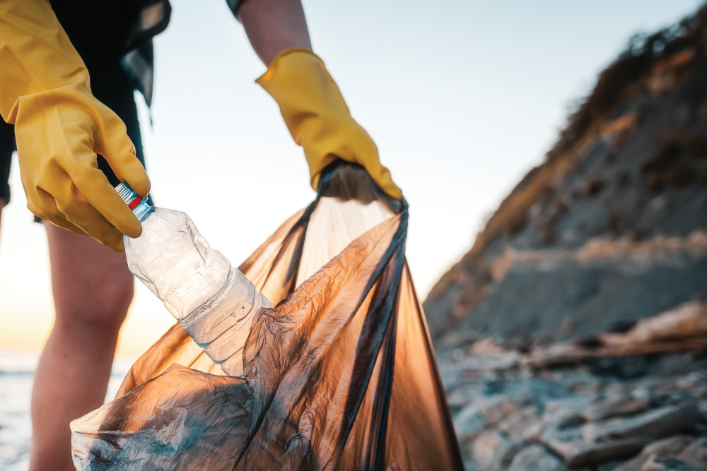 A woman volunteer puts a plastic bottle in a polyethylene bag.