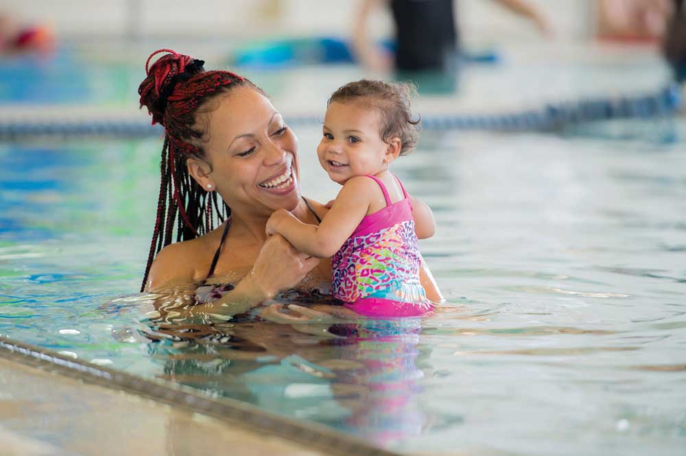 Mother and daughter are playing together in the public pool.