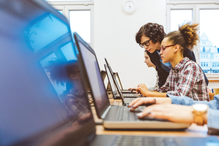 Student learning computer programming with teacher assisting