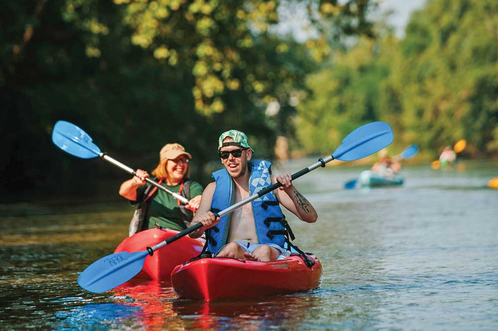 Group of people kayak down the Yadkin River.