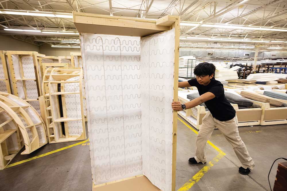High School student Cruz Ramirez moves a sofa frame in between construction stages at Shenandoah Furniture, where is working on an apprenticeship program with Surry Yadkin Works, in Mount Airy, NC.