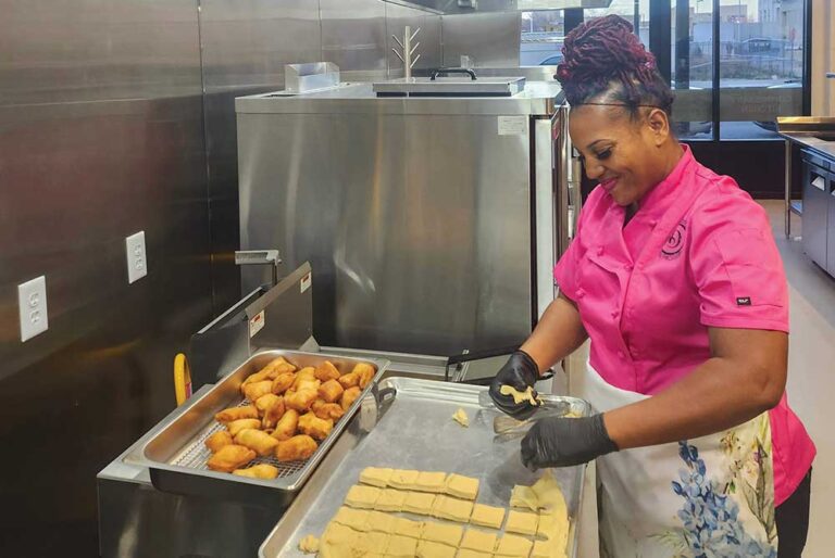 A chef prepares food at stainless steel counter tops in a commercial kitchen.