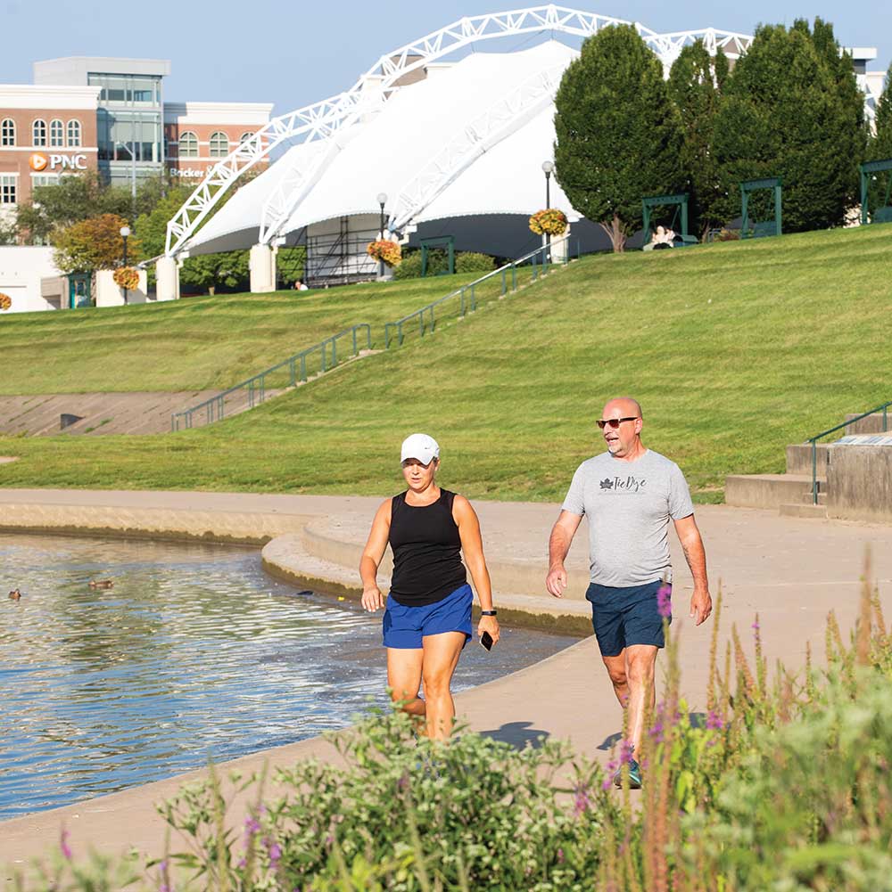 Cyclists and pedestrians using a paved trail along a riverfront park.