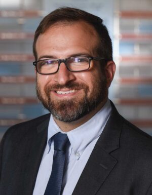 Professional headshot of Dr. Grant Turek wearing glasses and a suit tie.