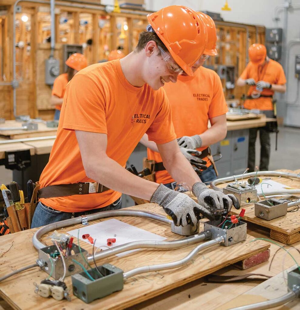 High school students wearing safety gear working with machinery inside a technical training lab.
