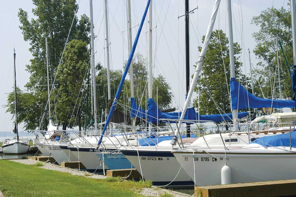 Several motorboats moored at wooden docks in a calm marina under a partly cloudy sky.