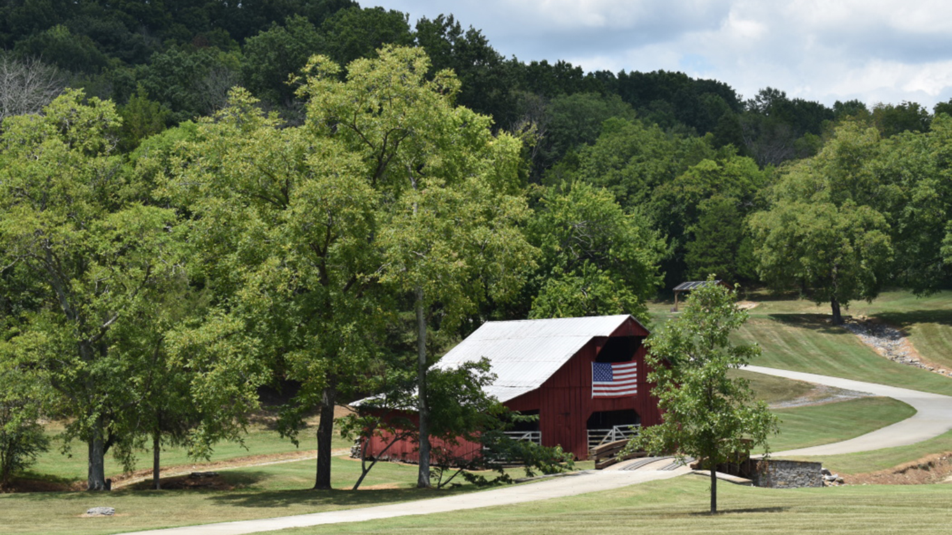 A red barn decorated with an American flag, set among the rolling hills of Goodlettsville, TN.