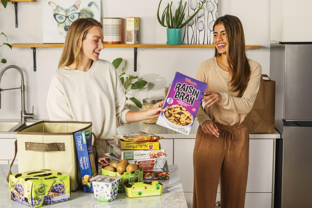two women unload grocery items, many with packaging created by Graphic Packaging