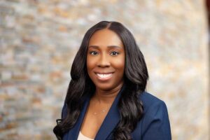 rofessional headshot of Zakiya Robinson smiling in a dark blue blazer.