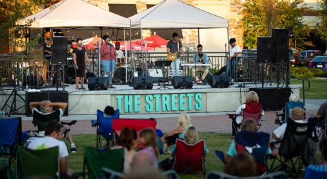 People sit in the grass while watching a concert that is held every Thursday in the summer at the Streets of Indian Lake in Hendersonville, Tennessee.