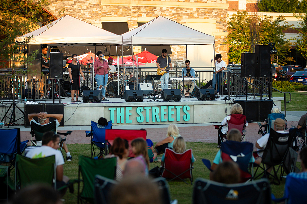 People sit in the grass while watching a concert that is held every Thursday in the summer at the Streets of Indian Lake in Hendersonville, Tennessee.