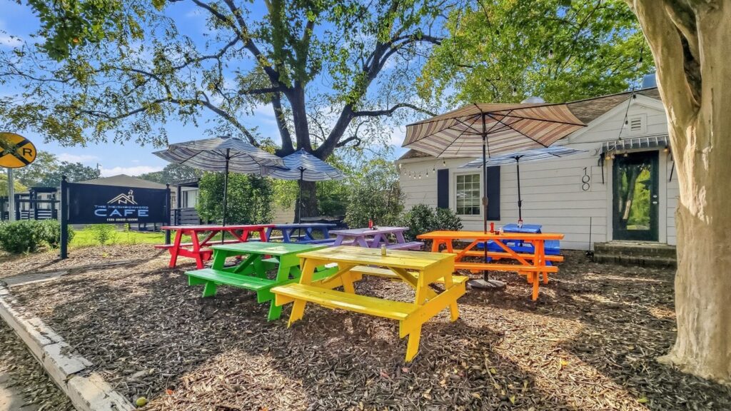 Outdoor tables under tree shade at The Neighbrohod Cafe in Huntersville