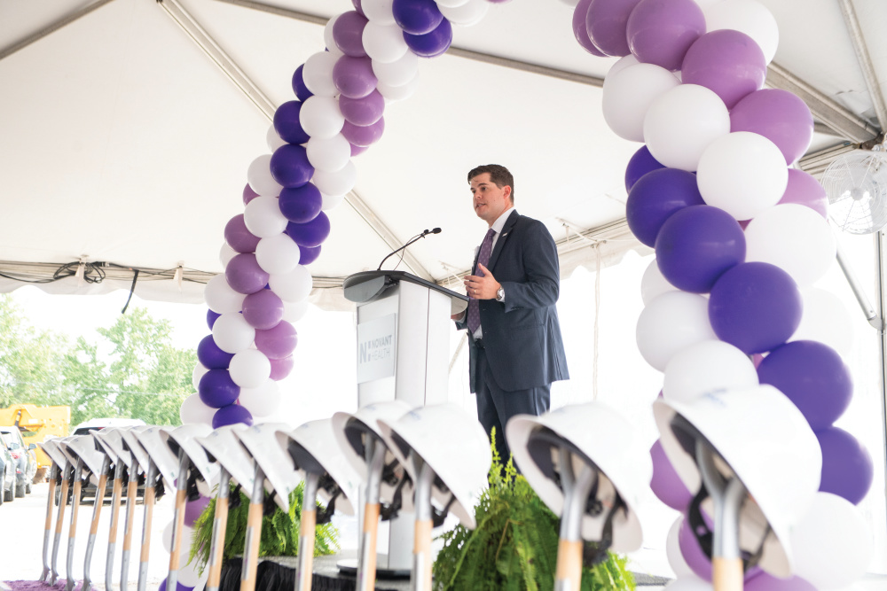 Man speaking into a microphone under a balloon arch