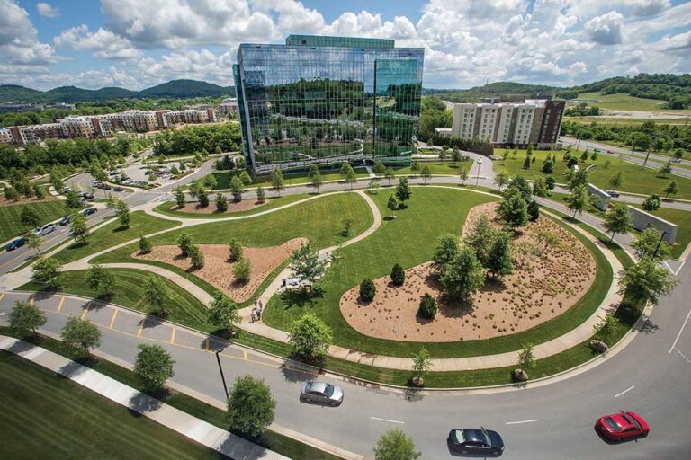 Aerial view of the glass Schneider Electric office tower surrounded by landscaped lawns and walking paths in Franklin, Tennessee