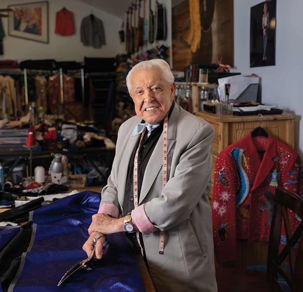 Fashion designer Manuel Cuevas holding fabric shears at a worktable in his Williamson County, Tennessee, design studio