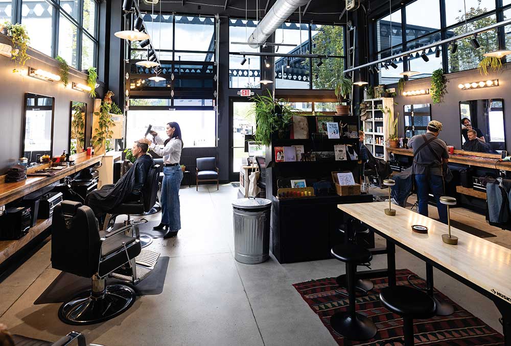 Barbers cutting clients’ hair inside the bright, industrial-style Scout’s Barber Shop at Canteen on Carothers in Franklin, TN