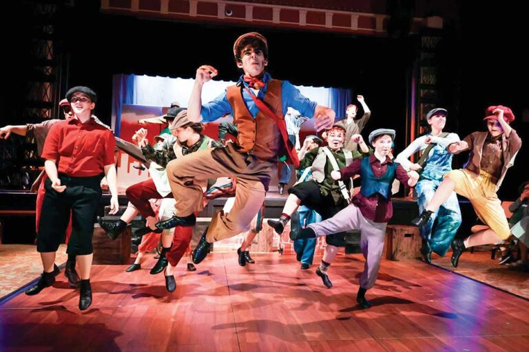 Teen actors in newsboy caps and vests jumping mid-dance during a musical at the Williamson County Performing Arts Center in Franklin, TN
