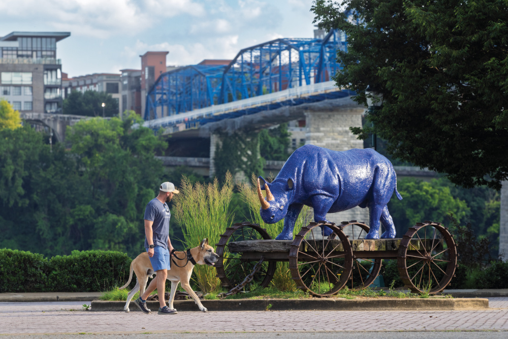 Spenser Rich with his dog Kane in front of Rhino Pull Toy scultpure by artist John Petrey in Coolidge Park in the North Shore neighborhood of Chattanooga, Tennessee.