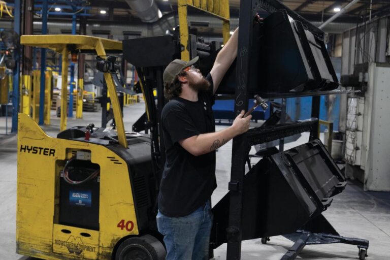 Employees move buckets around the manufacturing floor at Virnig Manufacturing in Pikeville, Tennessee.