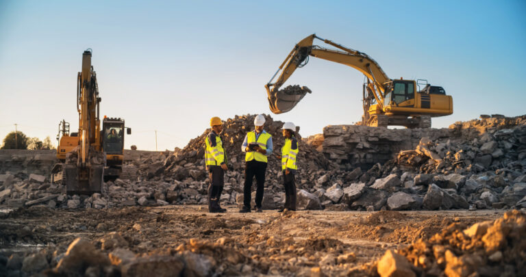 Construction Site With Excavators on Sunny Day: Diverse Team Of Male And Female Specialists Discussing Real Estate Project. Civil Engineer, Architect And Investor Talking About Apartment Building.