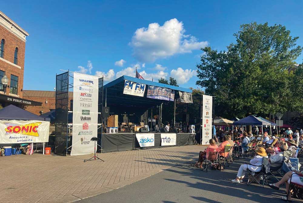 Bluegrass band playing banjo, fiddle and upright bass on an outdoor stage in Franklin, Tennessee